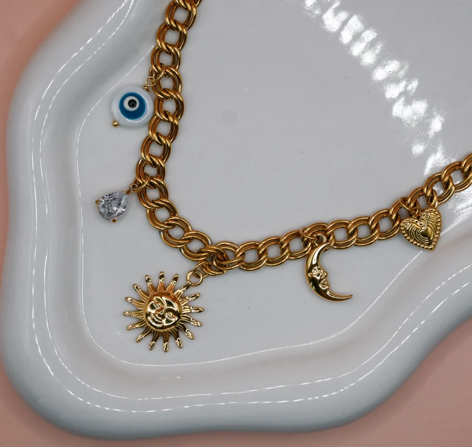 Soleil Gold Steel Charm Necklace with 18K gold-plated steel chain and hanging charms including steel heart, moon, peephole and a zircon. Water-resistant must-have summer jewelry for women.