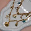 Soleil Gold Steel Charm Necklace with 18K gold-plated steel chain and hanging charms including steel heart, moon, peephole and a zircon. Water-resistant must-have summer jewelry for women.