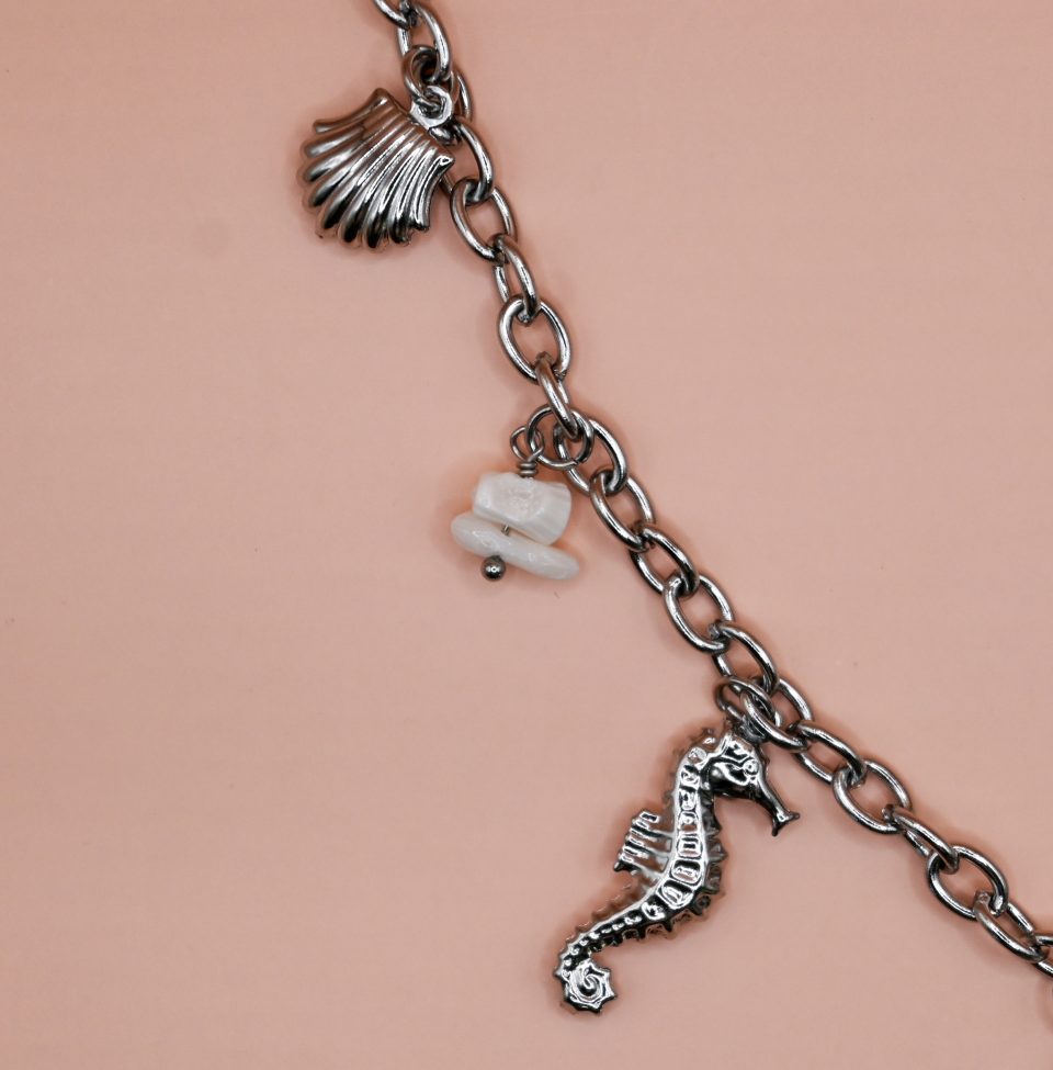 Starfish Silver Steel Charm Necklace with silver-plated steel chain and hanging charms including steel seashells, turtle, seahorse, white magnesite chips and a turquoise star. Water-resistant must-have summer jewelry for women.