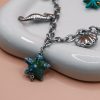 Starfish Silver Steel Charm Necklace with silver-plated steel chain and hanging charms including steel seashells, turtle, seahorse, white magnesite chips and a turquoise star. Water-resistant must-have summer jewelry for women.