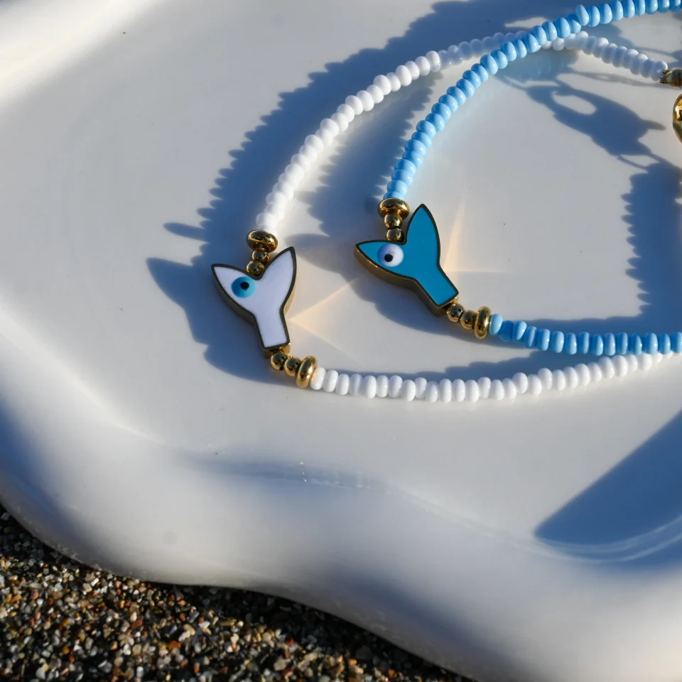Summer steel mermaid tail anklet with evil eye turquoise. Featuring a gold plated steel chain that fluctuates, turquoise glass grommets and a central steel charm with mermaid tail. Water-resistant summer jewelry for every woman.