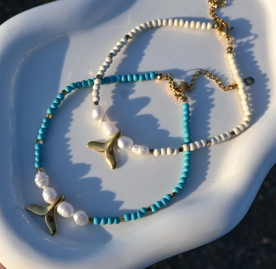 Summer steel mermaid tail pearl anklet with turquoise howlite stones. Featuring a gold plated steel chain that fluctuates, freshwater pearls and a central gold steel charm with mermaid tail. Water-resistant summer jewelry for every woman.