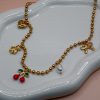 Gold steel charm necklace with cherries, teddy bear, pearl, heart, and bow steel charms on a trendy steel bead chain. Bold spring jewelry for 2026. Hot summer jewelry trends for 2026.