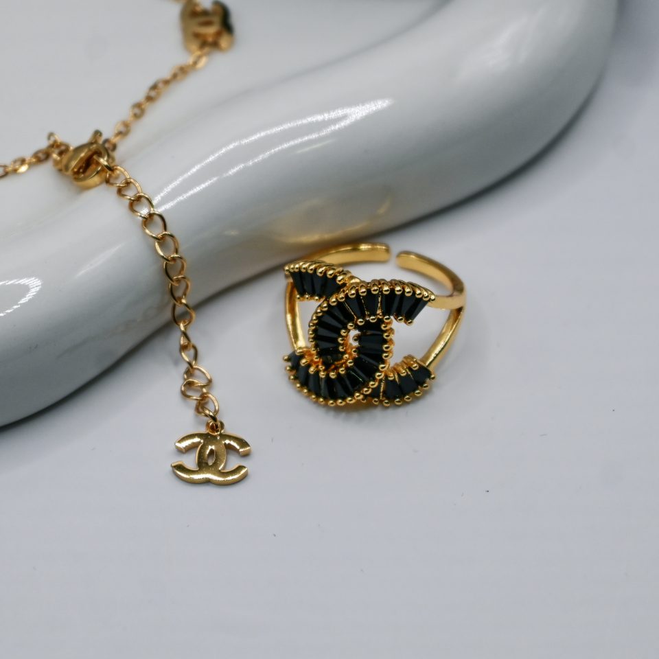 a chanel-isnpired adjustable ring made of metal alloy with high-quality gold plating and black crystal adornments.