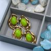 Y2K-inspired earrings made of durable stainless steel with 18-karat gold plating, featuring an irregular frame and light green resin stones.