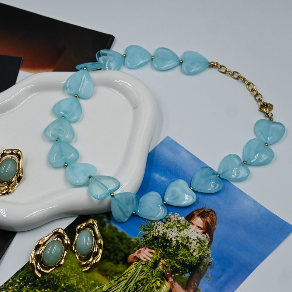 Light blue resin hearts with delicate marble-effect veining, stainless steel chain with 18K gold plating, gold-plated steel details.