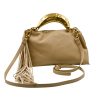 Gloria sand handbag, crafted from high-quality synthetic leather with a smooth texture. It features a statement metal handle in a gold shade with a hammered finish. It includes decorative suede tassels and a detachable leather strap.