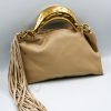 Gloria sand handbag, crafted from high-quality synthetic leather with a smooth texture. It features a statement metal handle in a gold shade with a hammered finish. It includes decorative suede tassels and a detachable leather strap.