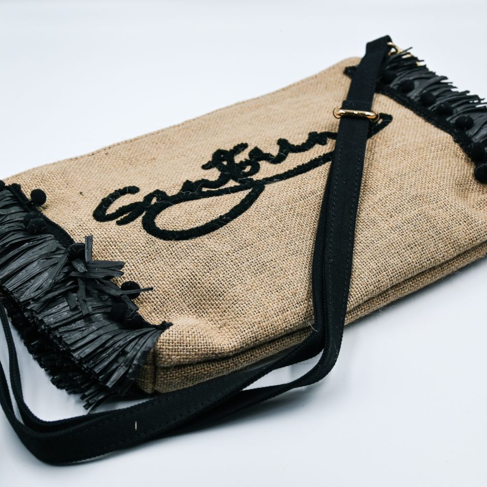 Black raffia clutch bag with embroidered Santorini detail and decorative tassels.